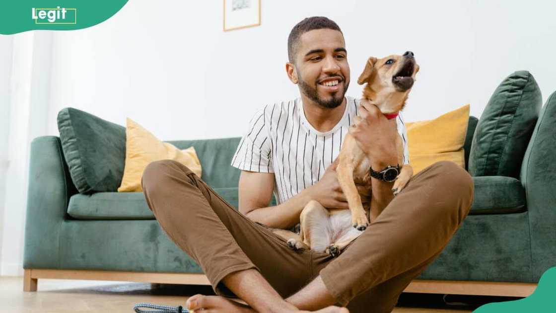 A man sitting on the floor while holding his dog