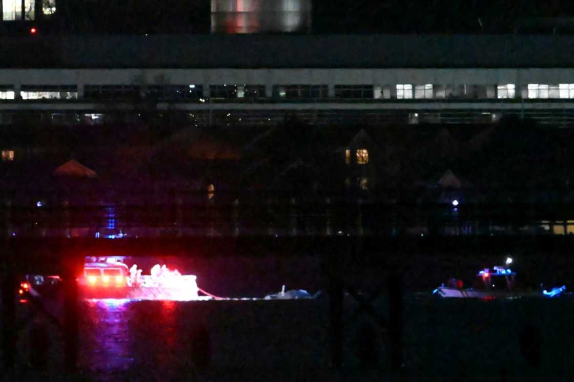 Two rescue boats pull debris from the water after a US passenger jet and a military helicopter crashed over the Potomac River near Reagan National Airport in Washington