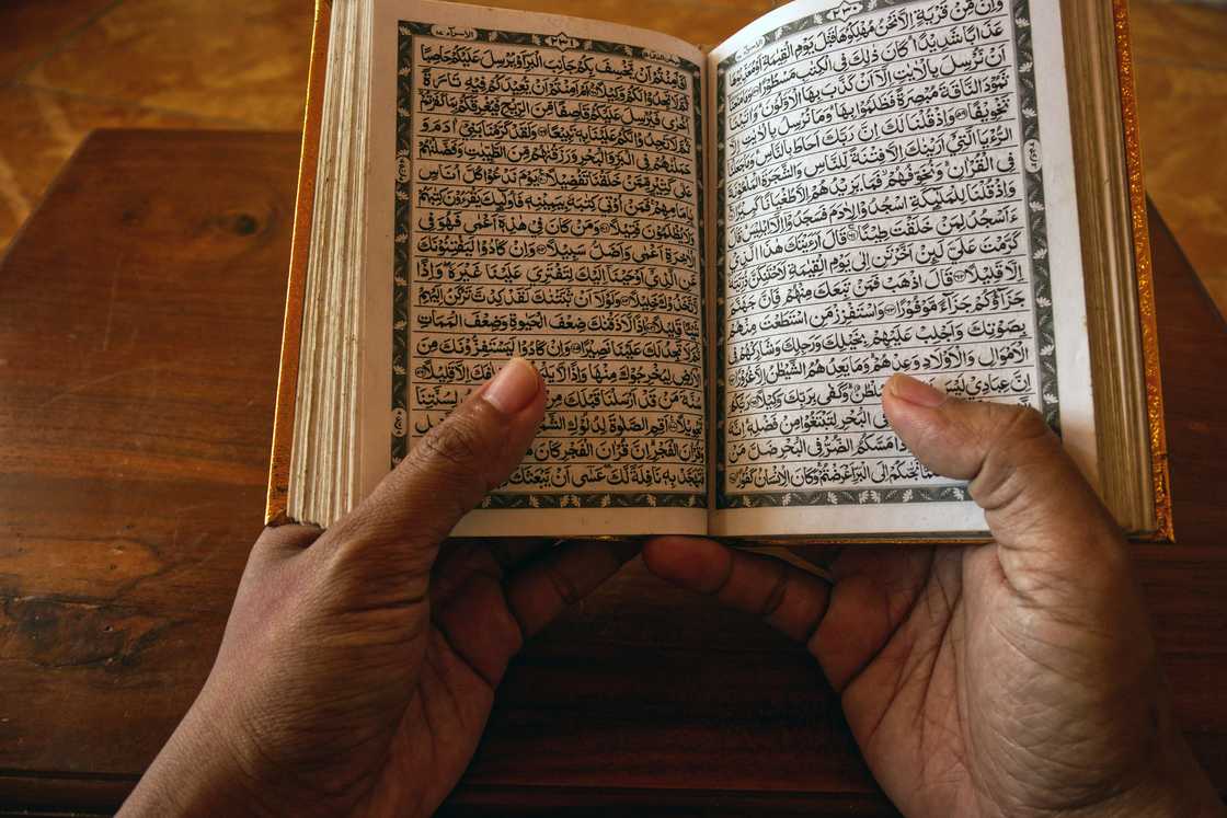 A person's hands are captured holding an open Quran A person's hands are captured holding an open Quran