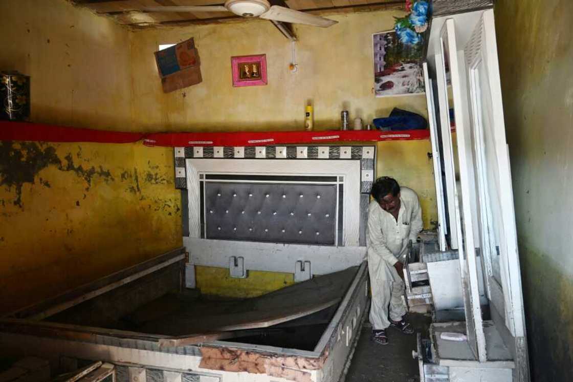 Mureed Hussain picks through flood-damaged furniture that was supposed to be part of a dowry for his daughter's impending marriage