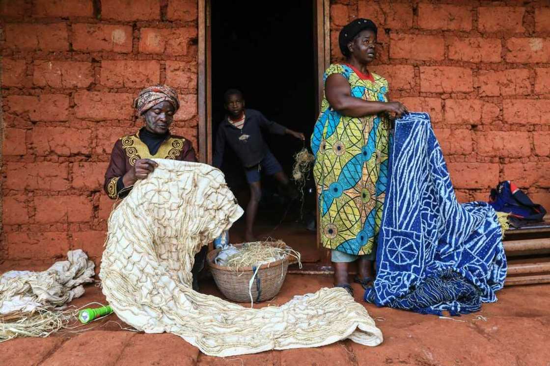 Yougo's cousin Sylvie Momo (right) holds up a dyed ndop outside her home in Baham Yougo's cousin Sylvie Momo (right) holds up a dyed ndop outside her home in Baham