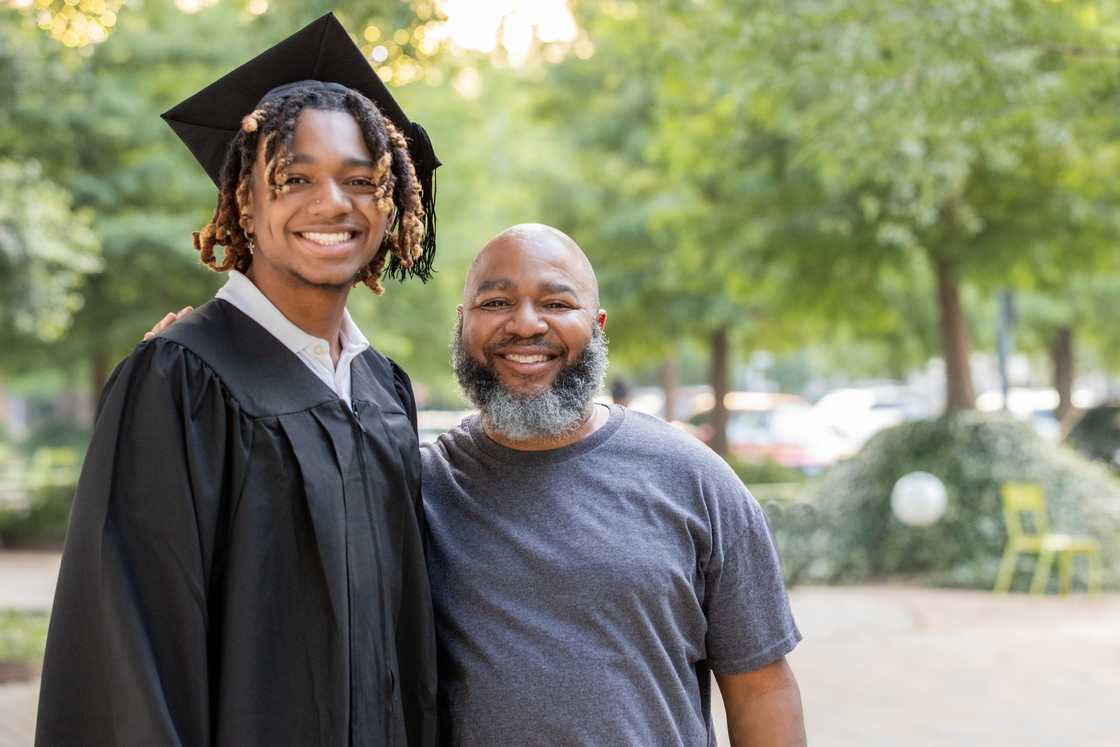 A young black man and his father pose for a family photo at a graduation celebration A young black man and his father pose for a family photo at a graduation celebration