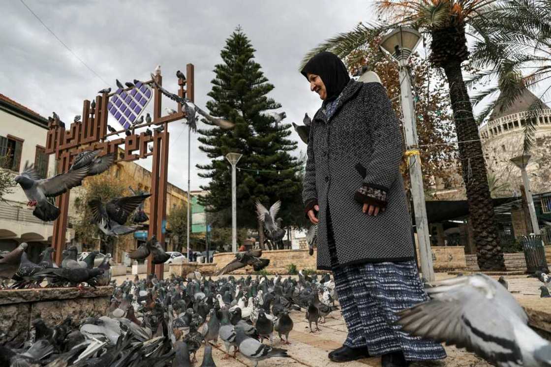A woman stands among pigeons at the square outside the Roman Catholic Basilica of the Annunciation in Nazareth in northern Israel