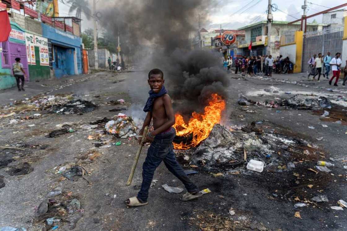 A mans walks past a burning barricade during a protest against Haitian Prime Minister Ariel Henry in Port-au-Prince on October 10, 2022 A mans walks past a burning barricade during a protest against Haitian Prime Minister Ariel Henry in Port-au-Prince on October 10, 2022
