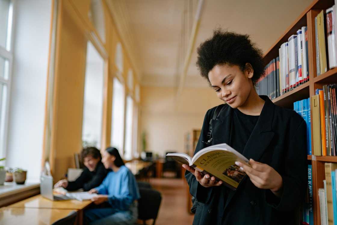 A student reading a book in a library A student reading a book in a library