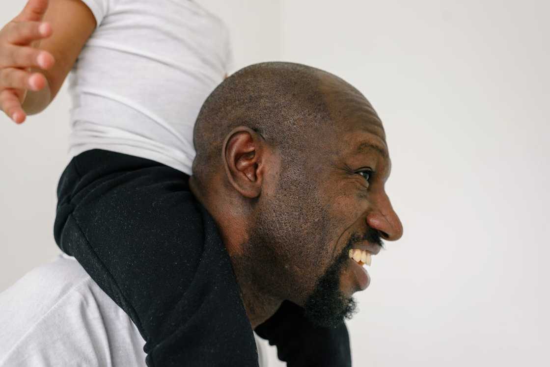 A father carries his young son on his shoulders.