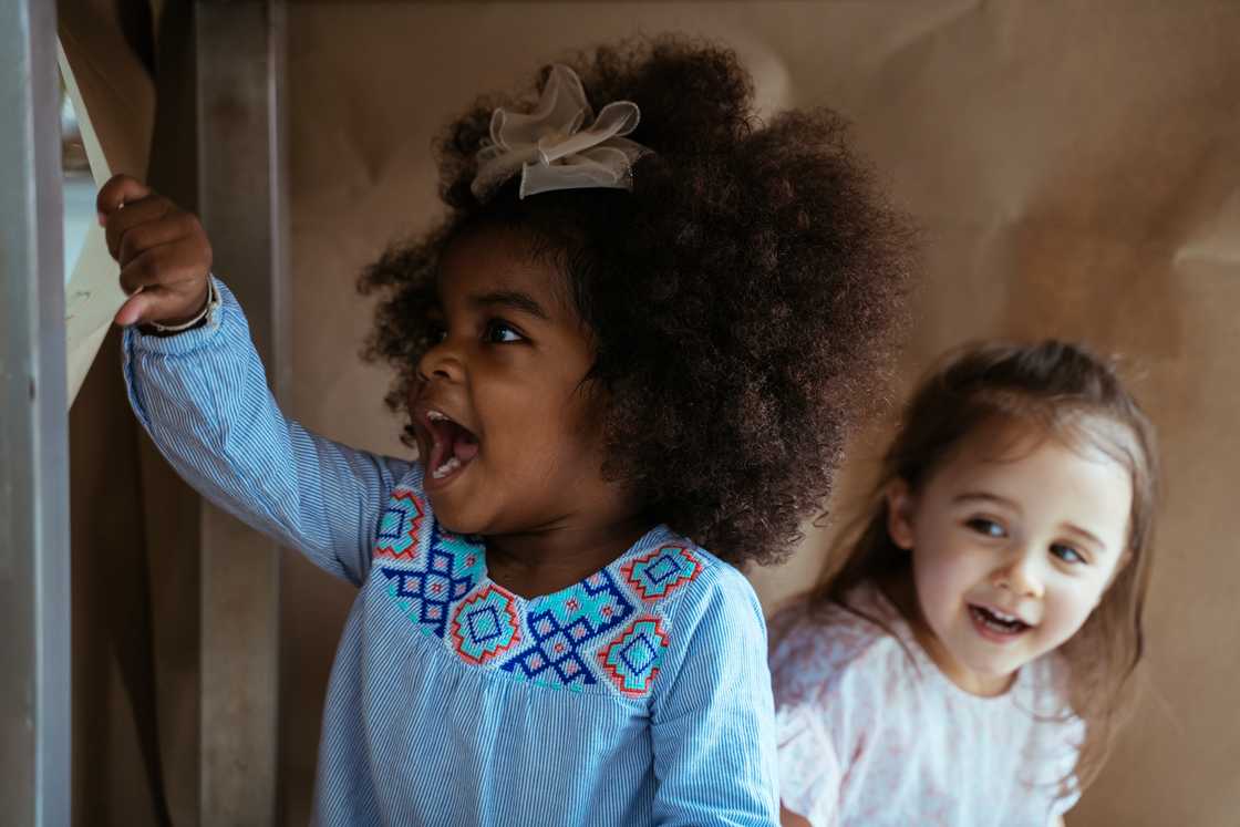 Two happy and curious young diverse girls