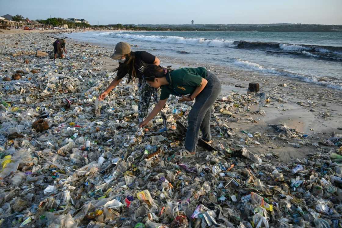 People look through plastic and other debris washed ashore at a beach on Indonesia's resort island of Bali