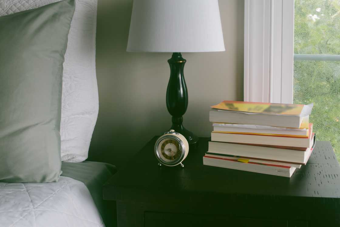 A nightstand, a clock, and a pile of books