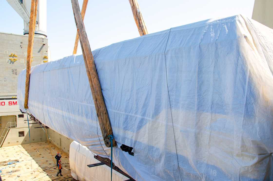 A covered vehicle is lowered beside a mausoleum during a symbolic burial.