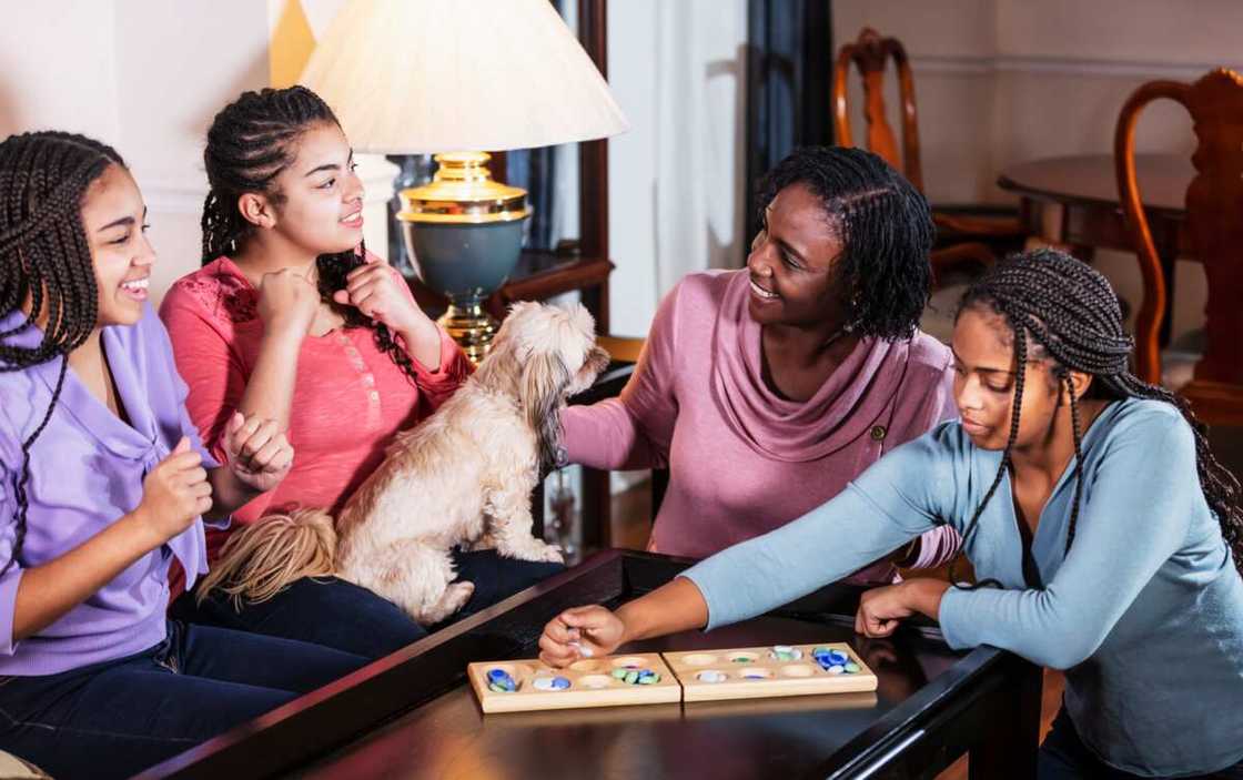 A mother and her three teenage daughters playing a game while talking