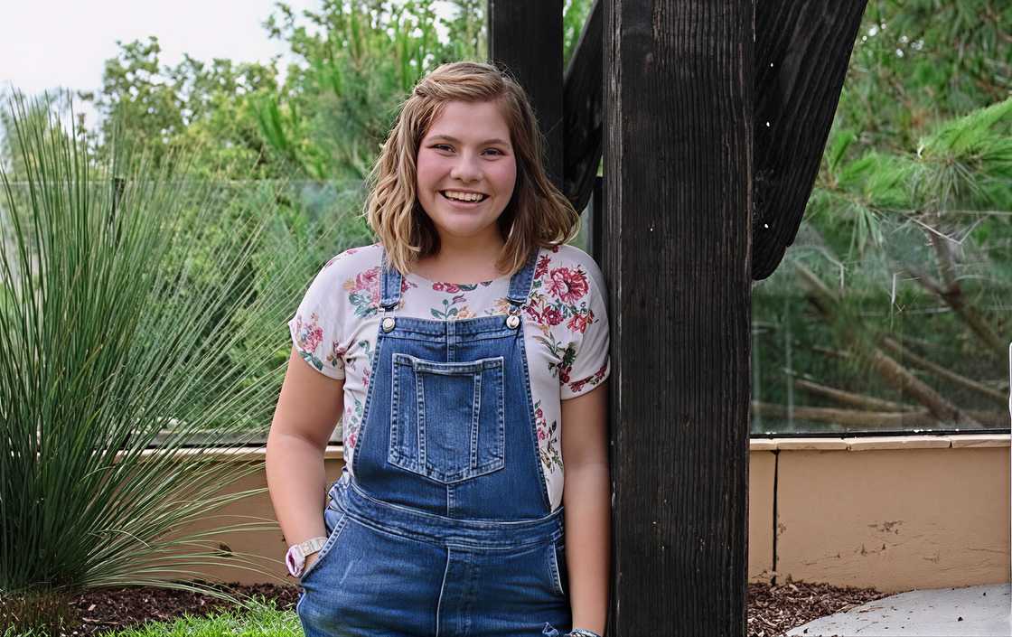 Claire Bassett pictured in blue denim overalls over a white short-sleeved shirt while standing outdoors. Claire Bassett pictured in blue denim overalls over a white short-sleeved shirt while standing outdoors.