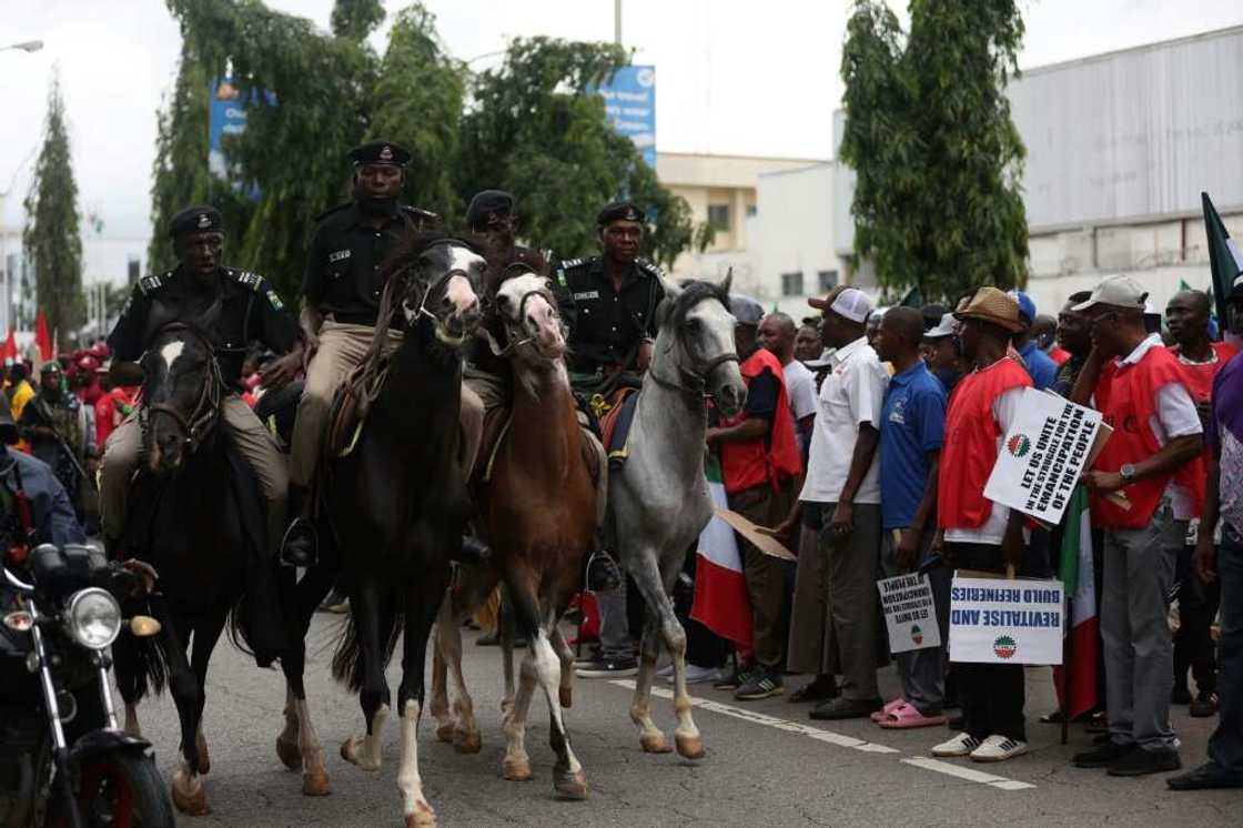 Mounted Nigerian police officers keep an eye on striking workers in Abuja Mounted Nigerian police officers keep an eye on striking workers in Abuja