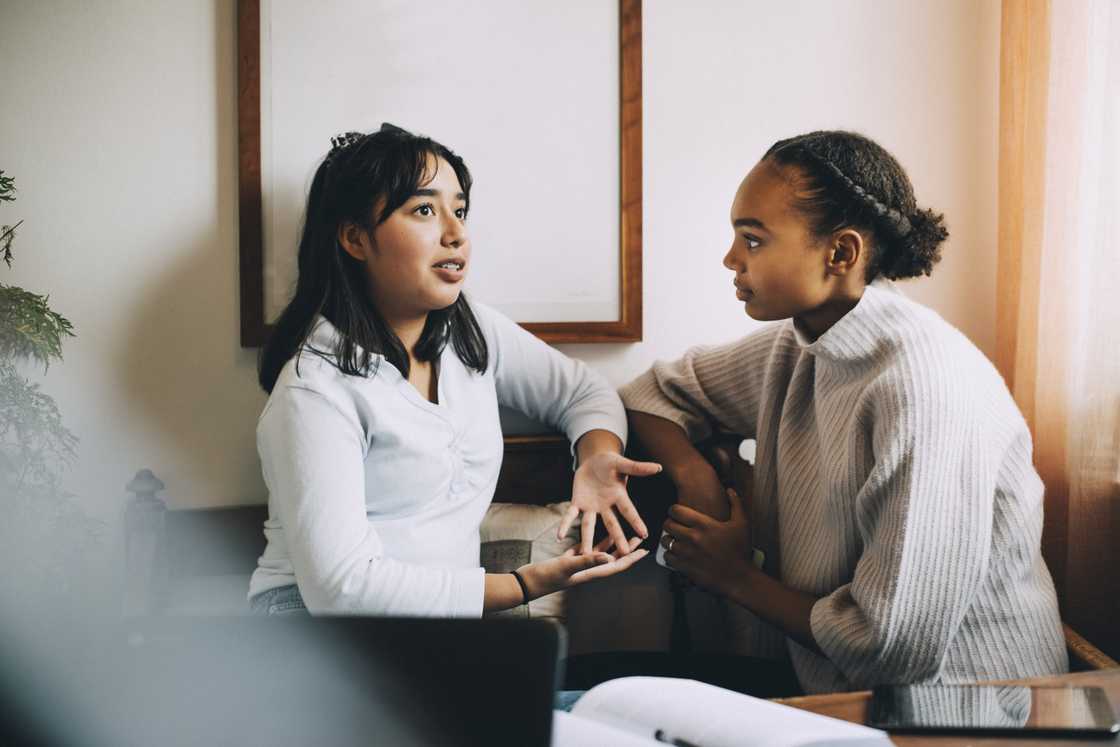 A teenage girl is gesturing while talking to a friend