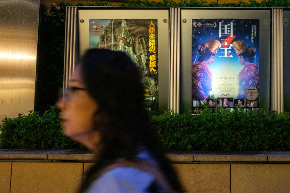 A woman walks past the poster of Japanese movie "Kokuho" (R) outside a cinema in Tokyo's Roppongi district on September 4, 2025. Lasting almost three hours, "Kokuho" is about two "onnagata", male players of female roles in kabuki, a rarefied form of classical Japanese theatre. Lee Sang-il's film, shot by Tunisian cinematographer Sofian El Fan, follows the friendship and rivalry of the son of a slain yakuza gangster and a boy born into a kabuki family. A woman walks past the poster of Japanese movie "Kokuho" (R) outside a cinema in Tokyo's Roppongi district on September 4, 2025. Lasting almost three hours, "Kokuho" is about two "onnagata", male players of female roles in kabuki, a rarefied form of classical Japanese theatre. Lee Sang-il's film, shot by Tunisian cinematographer Sofian El Fan, follows the friendship and rivalry of the son of a slain yakuza gangster and a boy born into a kabuki family.