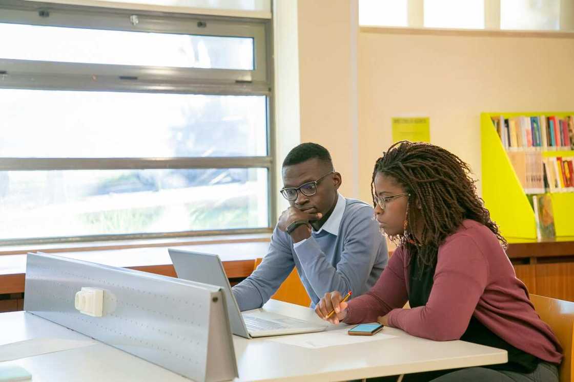 Two students doing a presentation for studies in a classroom. Two students doing a presentation for studies in a classroom.