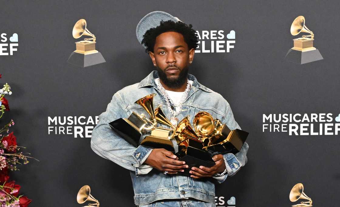 Kendrick Lamar poses as he holds five of his Grammy Awards