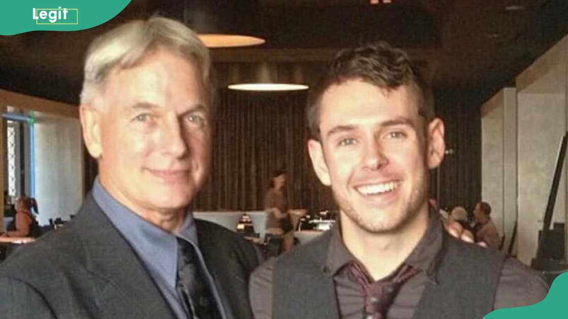 Mark Harmon and his son, Ty Christian Harmon, posing together indoors at an event venue Mark Harmon and his son, Ty Christian Harmon, posing together indoors at an event venue