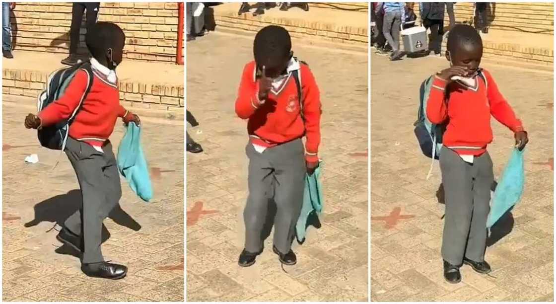 Black boy in red and grey school uniform dancing in school compound.