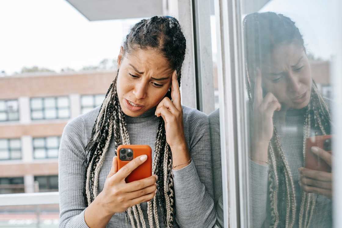 A young woman staring at her phone in shock. A young woman staring at her phone in shock.