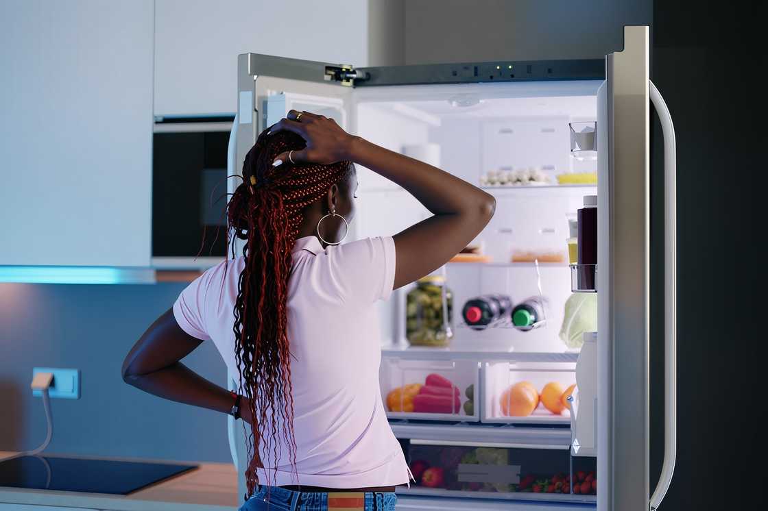 A woman is looking at food in a fridge A woman is looking at food in a fridge