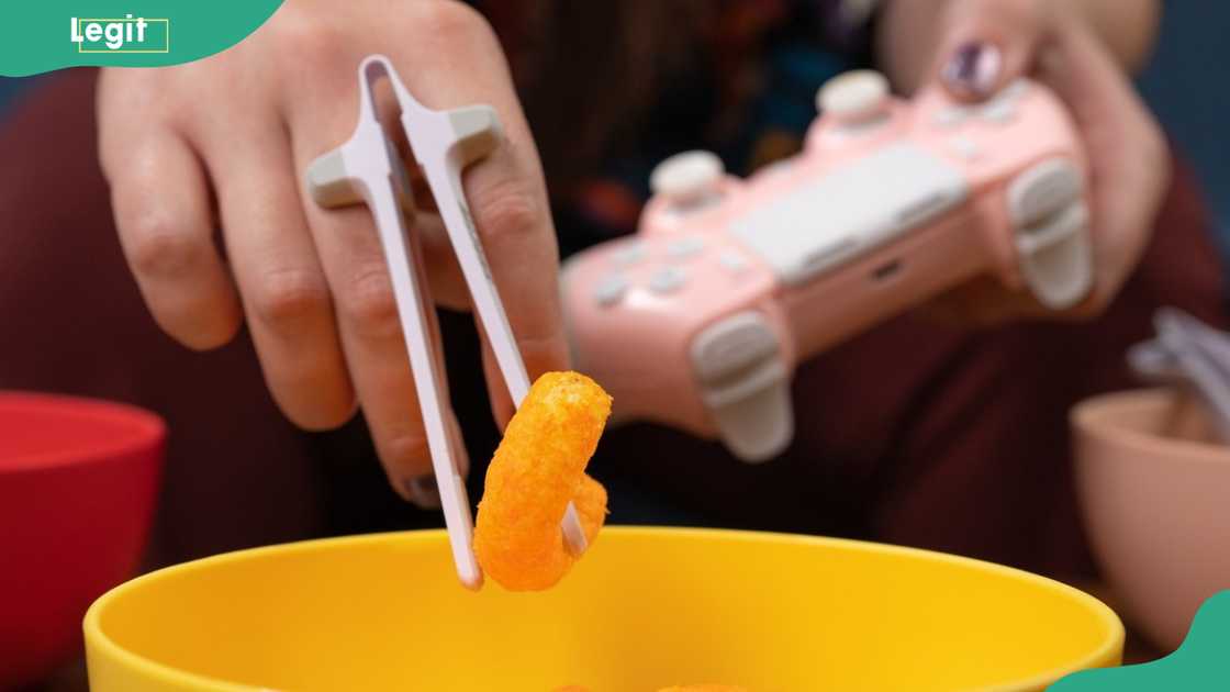 A person enjoys gaming while using a Snactiv hands-free snack holder A person enjoys gaming while using a Snactiv hands-free snack holder