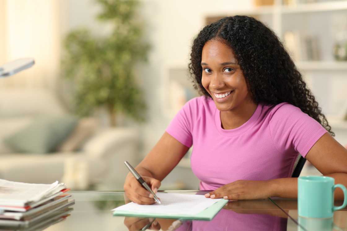A lady smiles as she fills out a form A lady smiles as she fills out a form