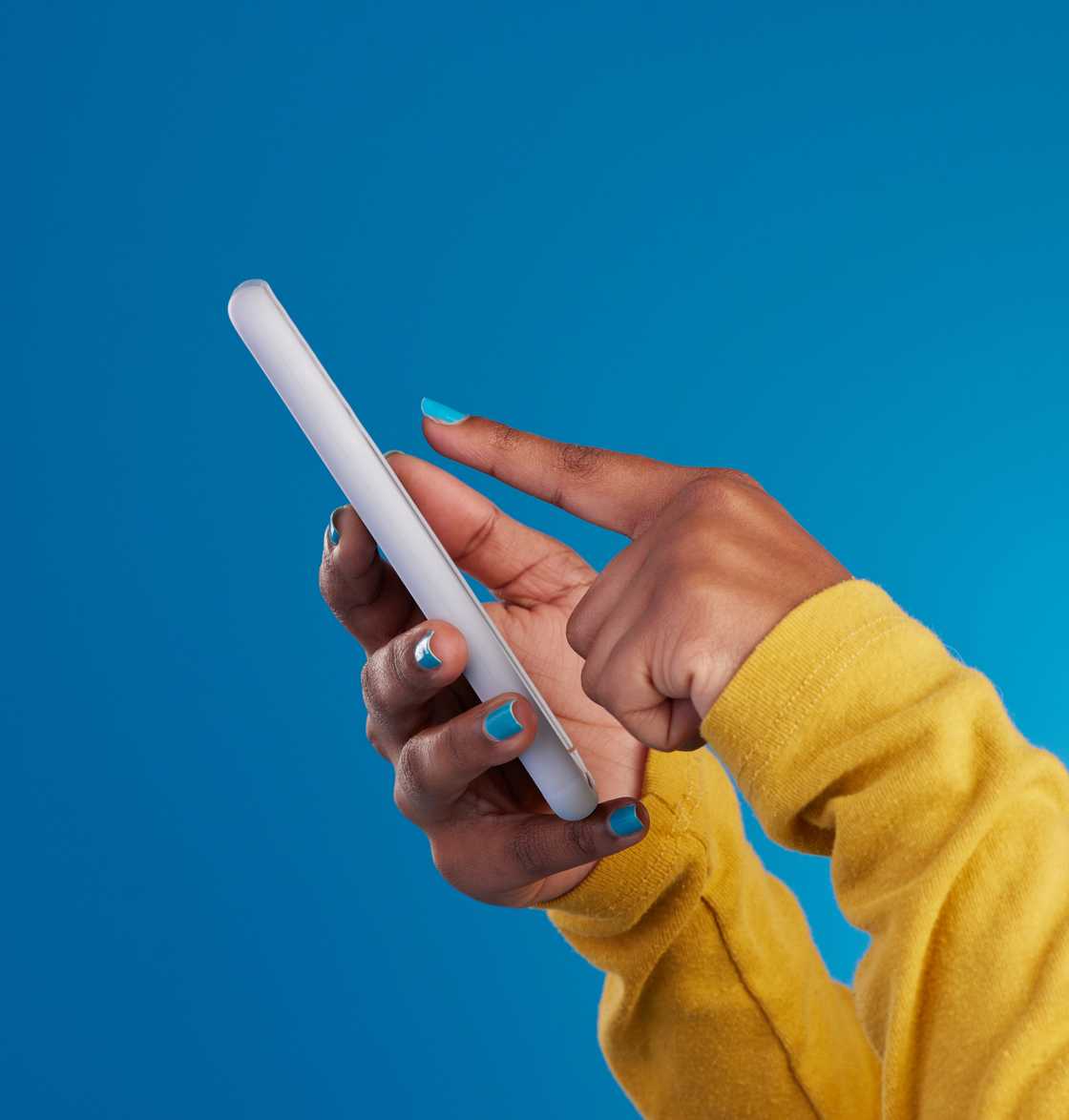 A close-up of two hands with blue-painted nails holding and tapping a white smartphone.