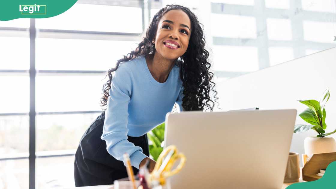 A female empyoee working on a laptop in a modern office space.