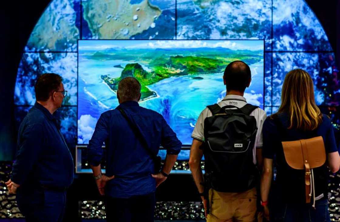 Visitors contemplate an 8K TV at the stand of South Korean consumer goods giant LG at the tech fair -- motto this year "energy efficiency"