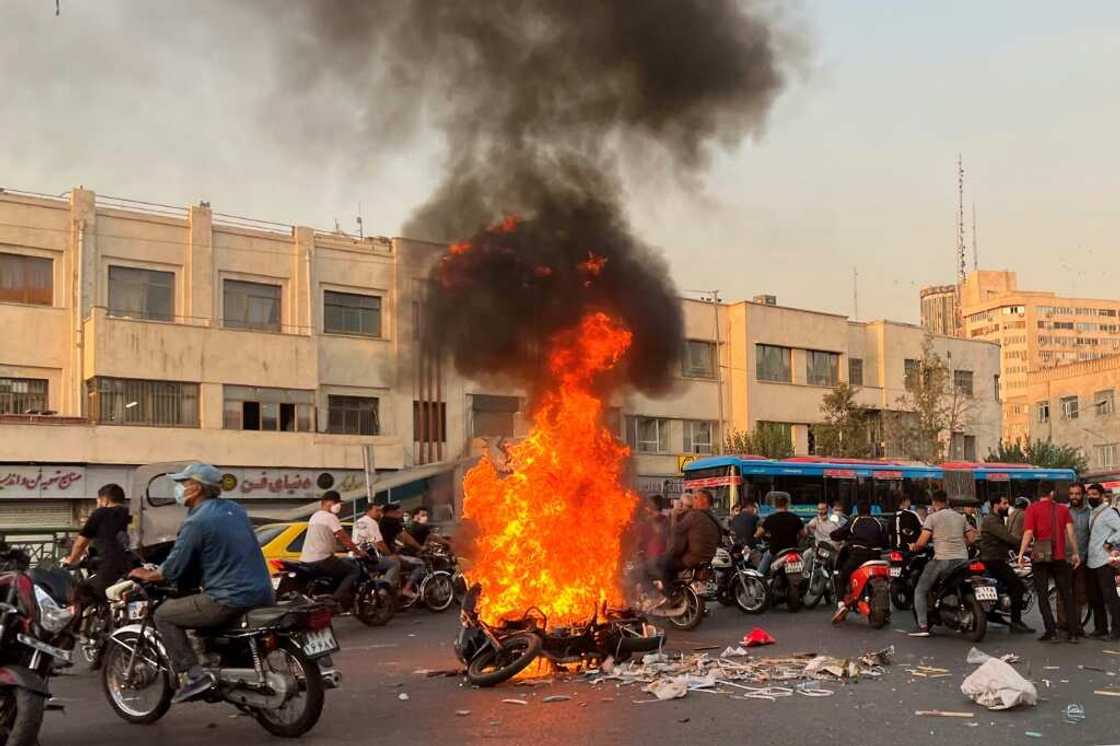 A picture obtained by AFP outside Iran shows people gathering next to a burning motorcycle in Tehran A picture obtained by AFP outside Iran shows people gathering next to a burning motorcycle in Tehran