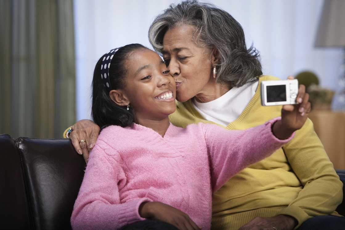 Older woman kisses young girl as she takes a selfie. Older woman kisses young girl as she takes a selfie.