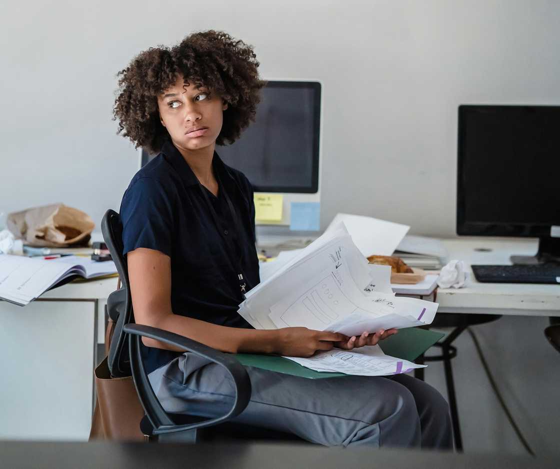 A tired woman in an office handling papers A tired woman in an office handling papers
