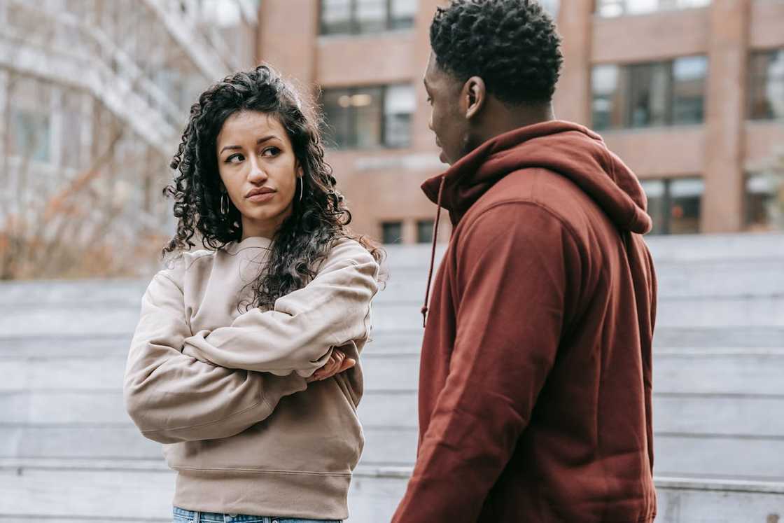 A woman crosses her arms and looks at a man during a disagreement.
