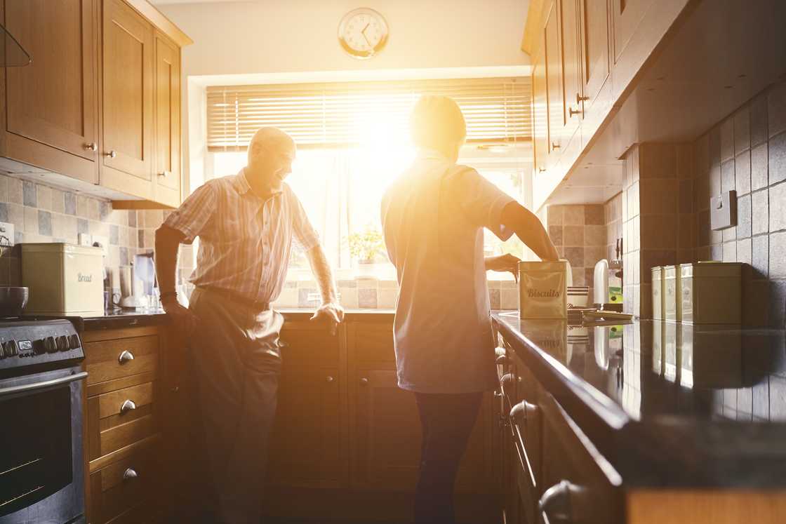Two people stand in a warmly lit kitchen. Two people stand in a warmly lit kitchen.