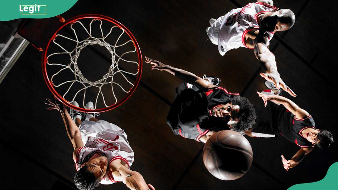 Basketball player dunking ball over opponents