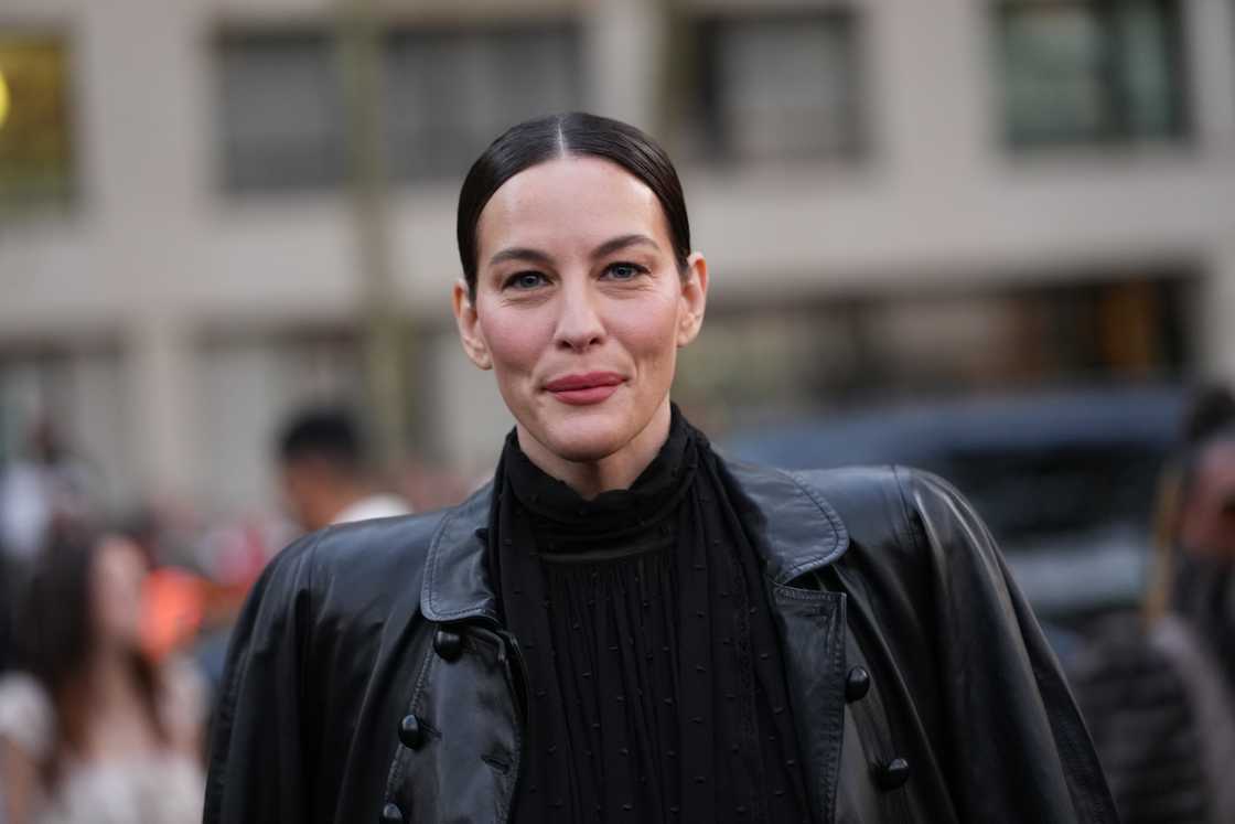 Liv Tyler wears sleek dark brown hair pulled into a low centre-parted ponytail during Paris Fashion Week
