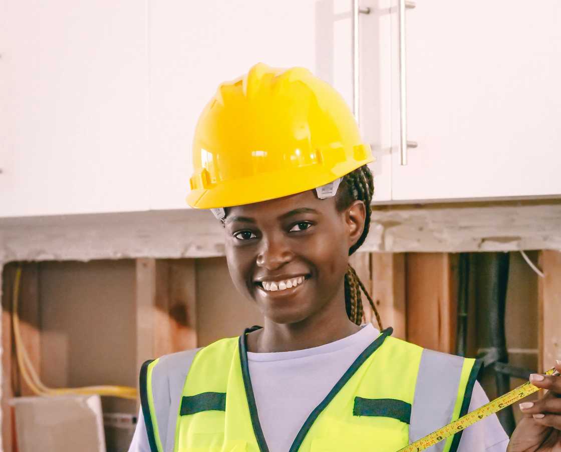 A woman engineer smiling while holding a measuring tape A woman engineer smiling while holding a measuring tape