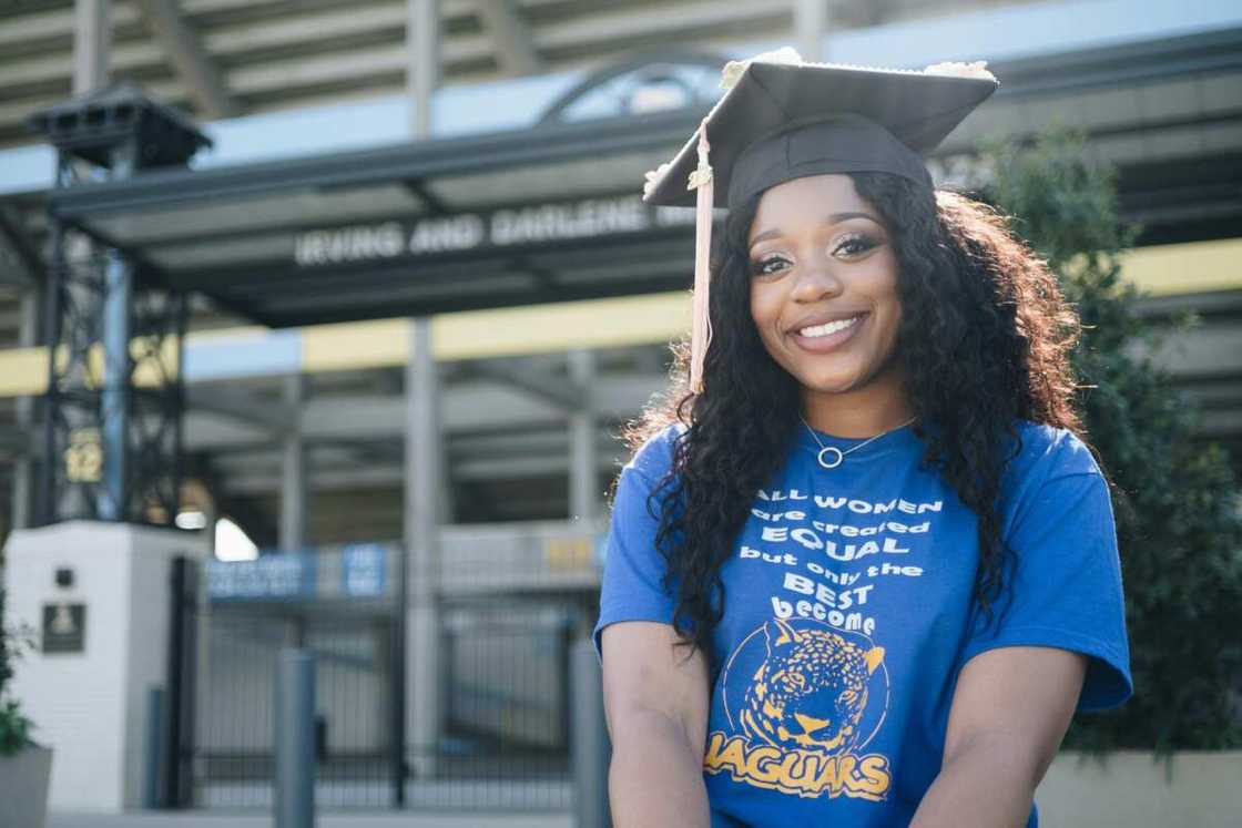 A university student wearing a blue T-shirt and a graduation cap