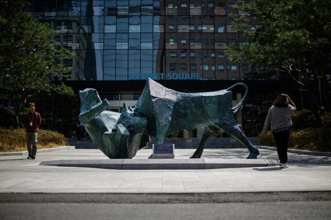 People walk past a bull and bear sculpture in front of the Korea Exchange building in Seoul People walk past a bull and bear sculpture in front of the Korea Exchange building in Seoul
