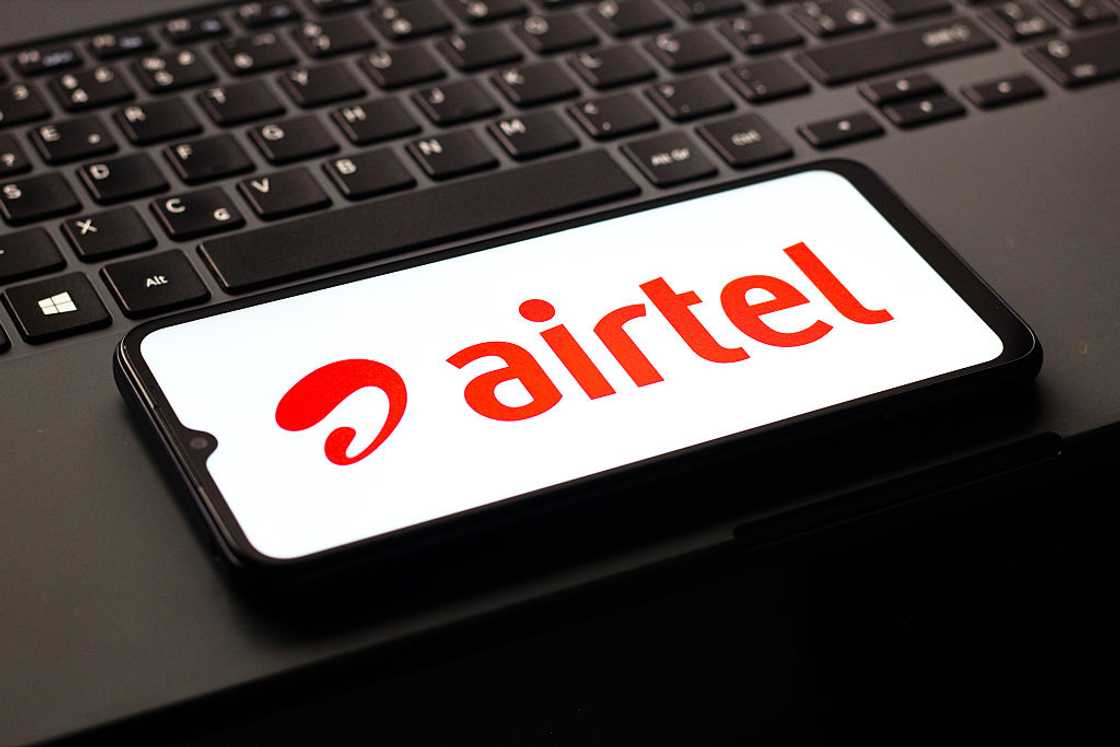 A phone with the red Airtel logo on its screen lies on a black laptop keyboard. A phone with the red Airtel logo on its screen lies on a black laptop keyboard.