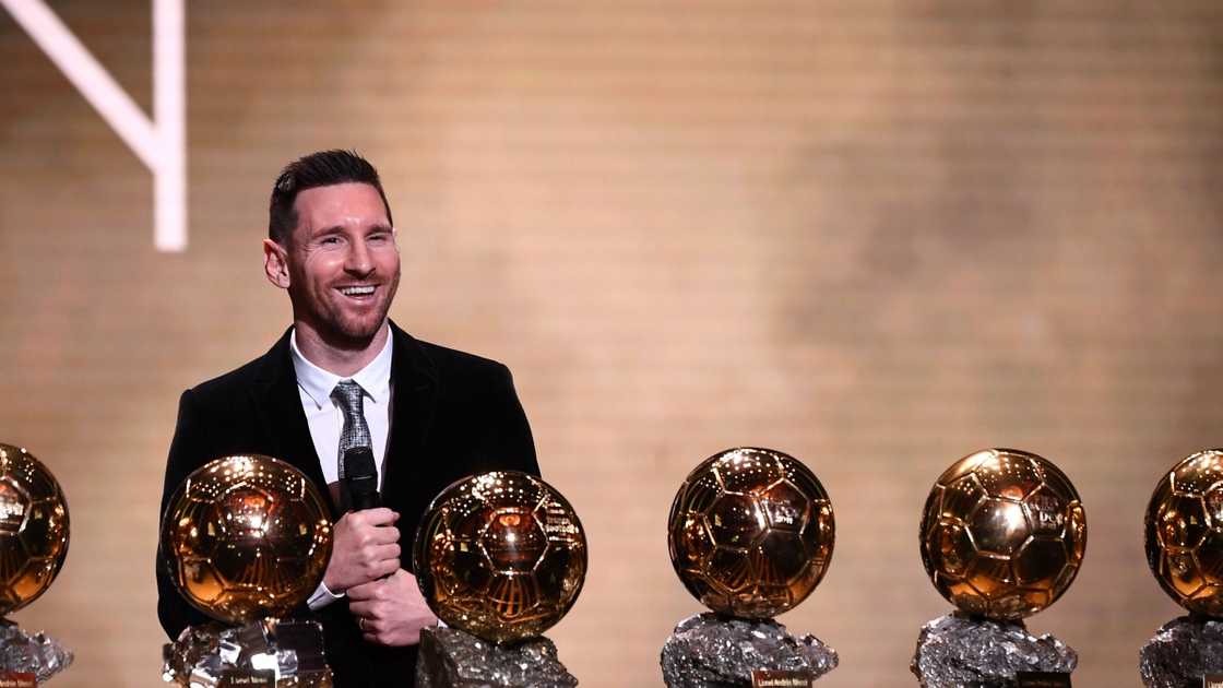 Lionel Messi laughs while posing infront of six Ballon d'Or trophies during his award ceremony.