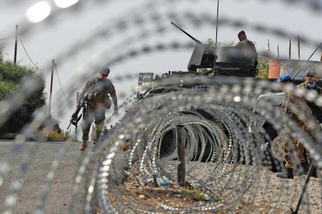 Lebanese army soldiers (L) stand by an infantry-fighting vehicle (IFV) near peacekeepers (R) of the United Nations Interim Force In Lebanon (UNIFIL) in Naqura along the border with northern Israel on Thursday