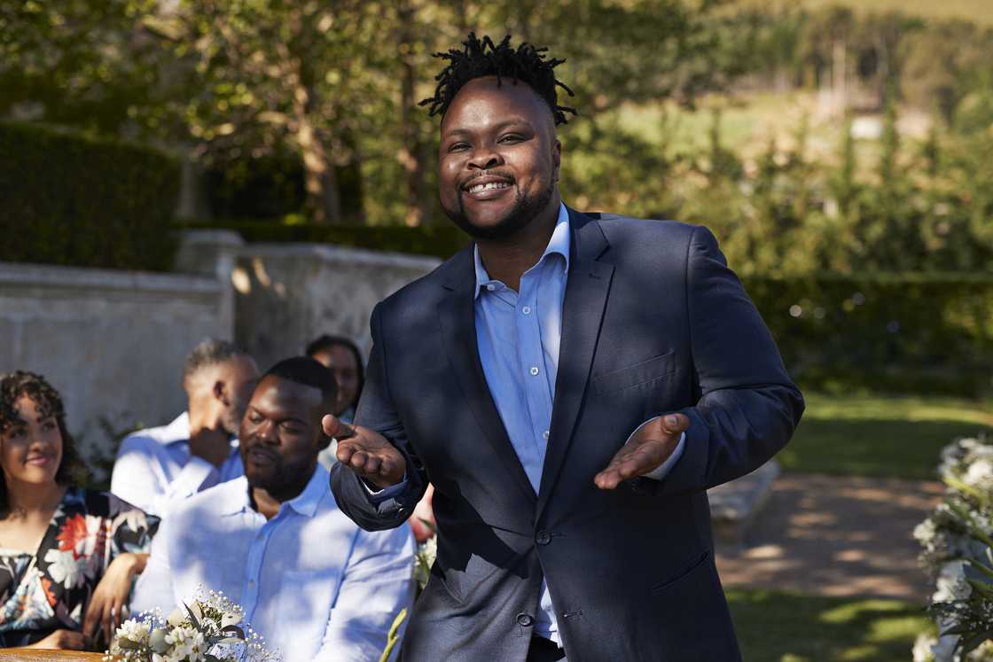 A smiling man in formals gesturing during ceremony. A smiling man in formals gesturing during ceremony.