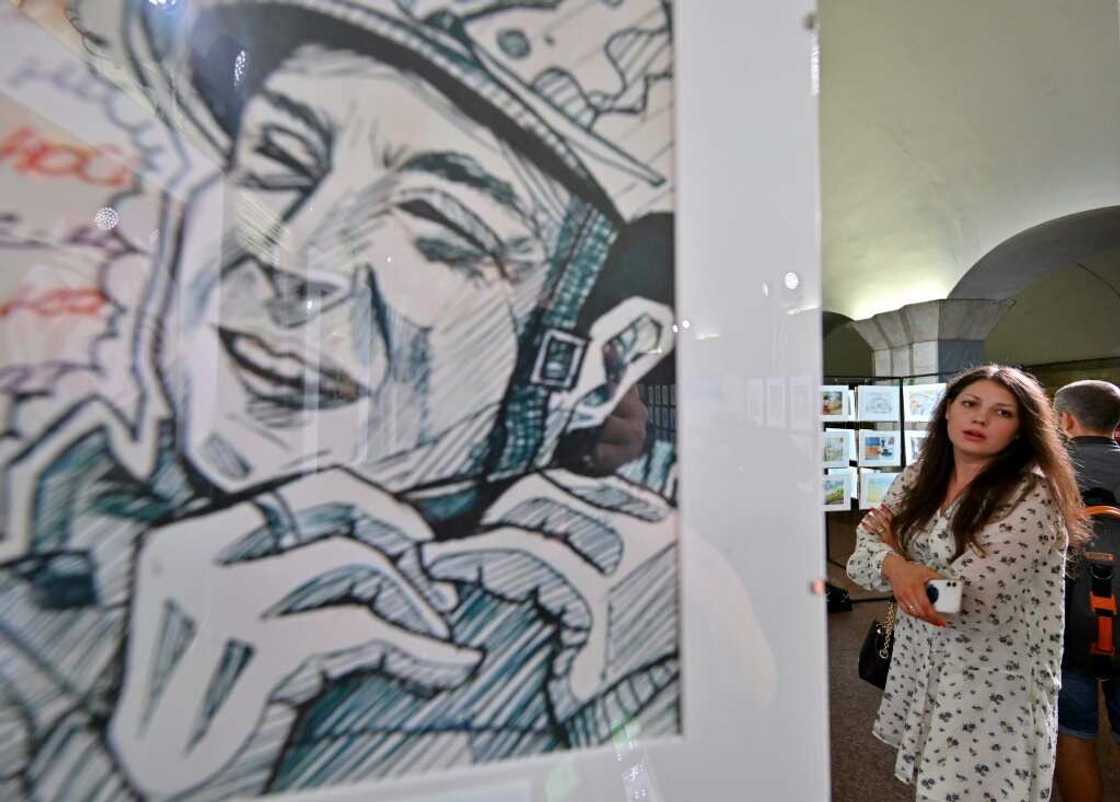 In one drawing, a smiling soldier straps on a helmet In one drawing, a smiling soldier straps on a helmet