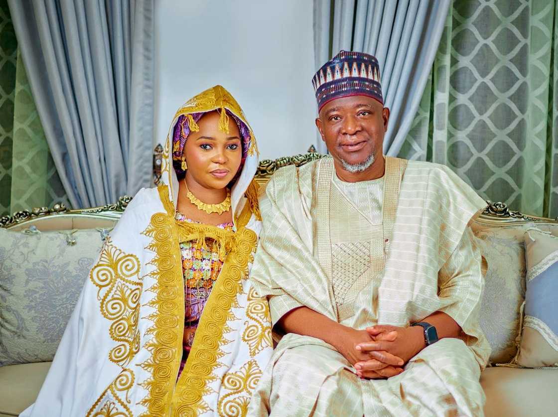 African couple in traditional attire seated together indoors.