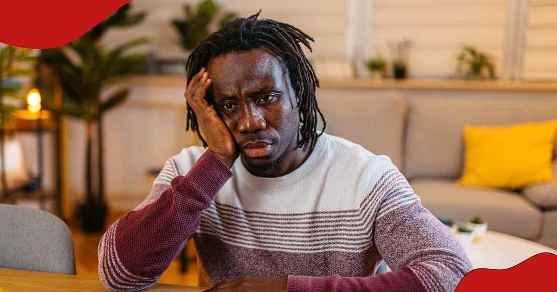 A man holds his cheek, lost in thought. A man holds his cheek, lost in thought.