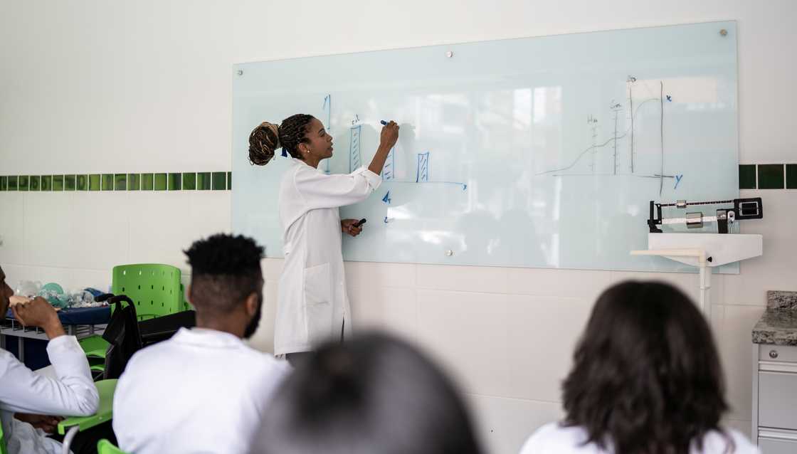 A teacher writes on a white board during a pharmacy lesson. A teacher writes on a white board during a pharmacy lesson.