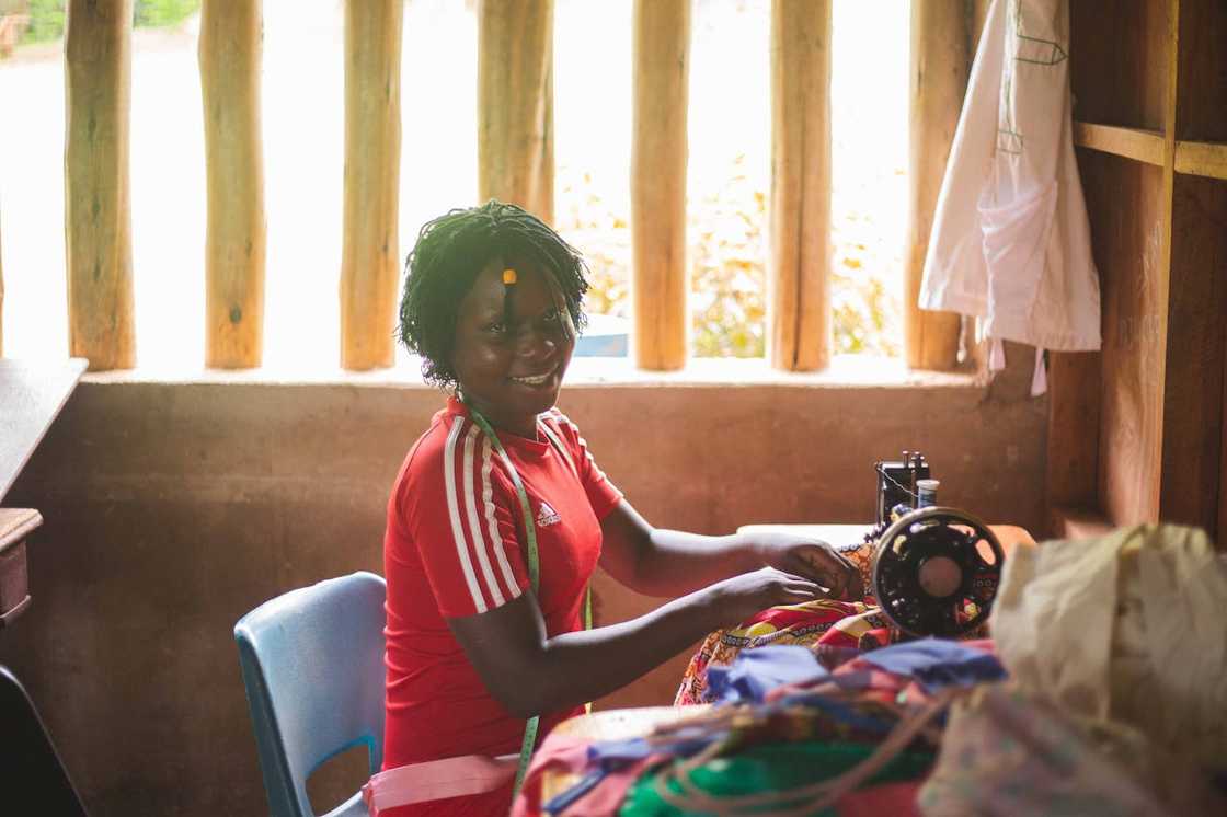 A woman sewing colourful fabric on a manual sewing machine.