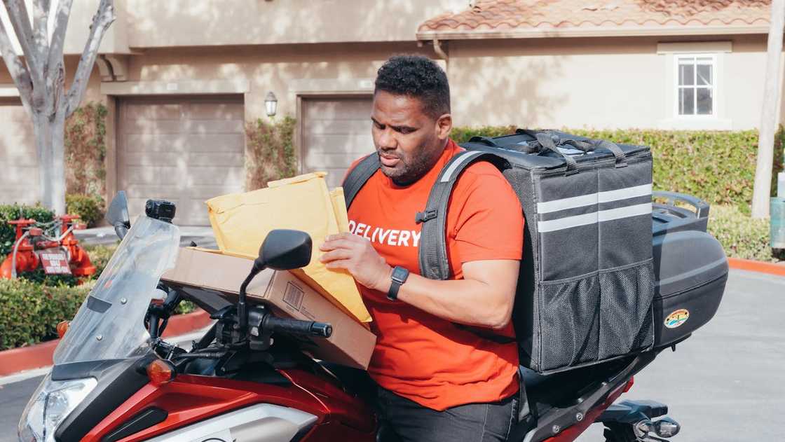 Courier checking parcels beside a motorbike during deliveries.